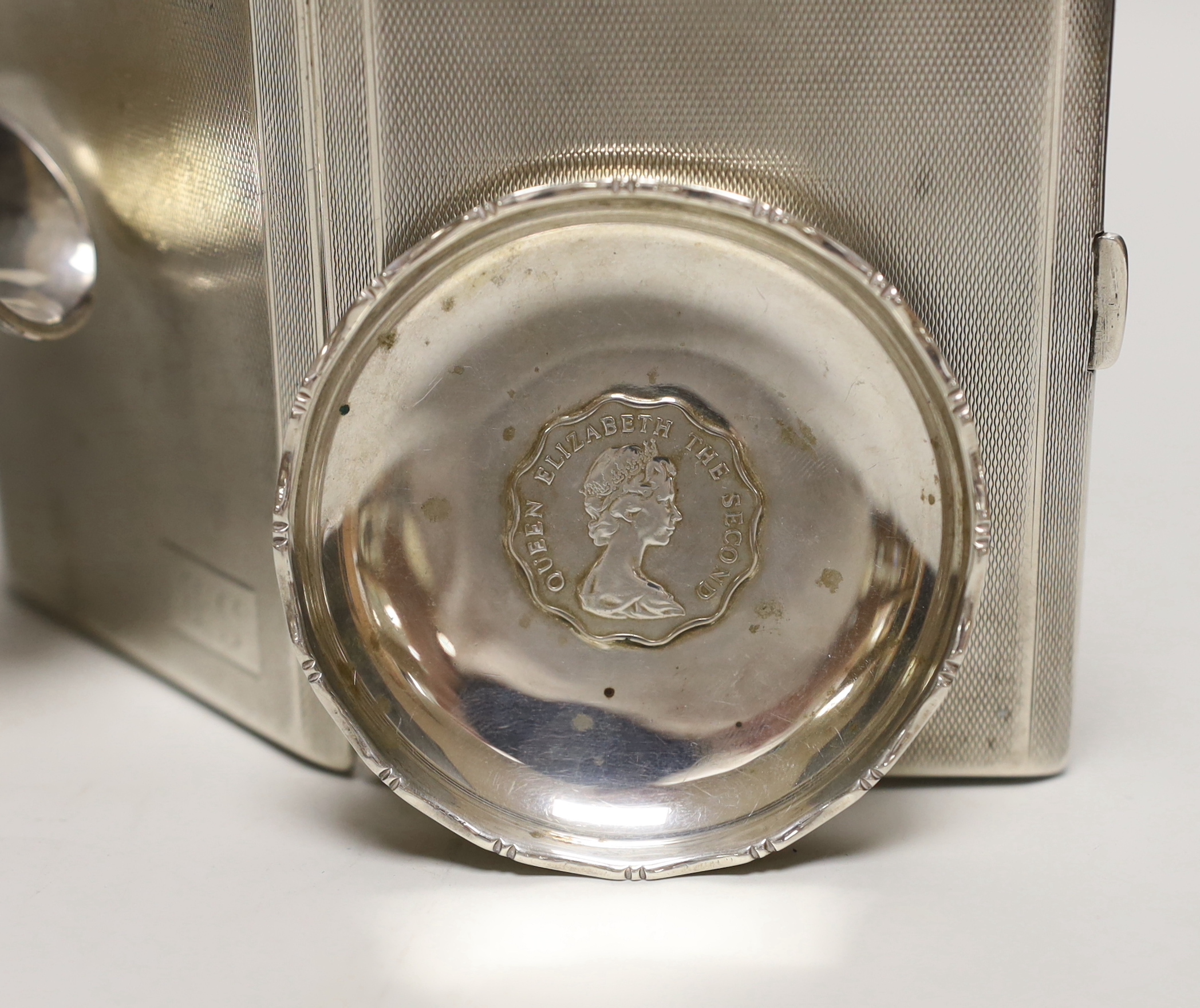 A George V engine turned silver cigarette case, 11.3cm a white metal sauceboat and a Wai Kee sterling pin dish.